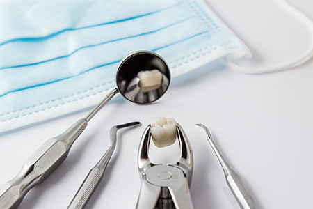 The image shows a collection of dental tools including a toothbrush with toothpaste on it resting on a blue cloth, set against a white background.